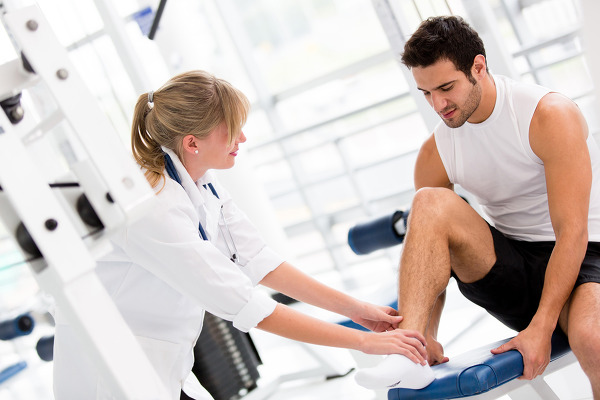 Injured man at the gym feeling pain in his ankle